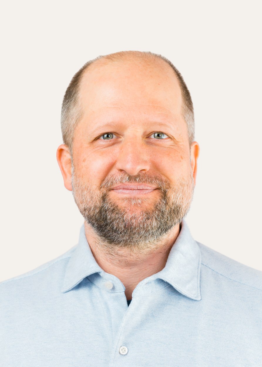 Christian Weidl, Osteopath und Akupunkteur in München, Portraitbild vor einer weißen Wand mit hellblauem Hemd